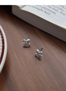 Close-up of S925 sterling silver brushed fleur-de-lis earrings with a tiny diamond center