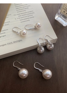 Détail de boucles d'oreilles en argent S999 avec perles et zircons sur des livres anciens