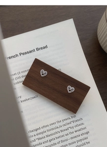 Macro shot of silver heart studs with bow detail and white cubic zirconia on wood