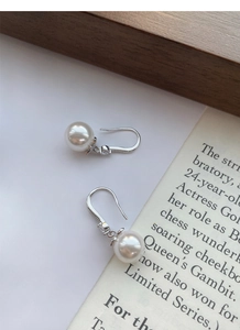Détail de boucles d'oreilles perles en argent S999 avec zircon sur fond de magazine