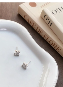 Detailed view of S999 sterling silver clover stud earrings with zircon on a ceramic tray