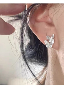 Detailed close-up of a S999 sterling silver butterfly stud earring worn on the earlobe
