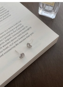 Macro detail of silver S999 bow-knot heart stud earrings with sparkling pavé cubic zirconia