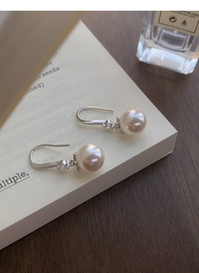 Vue détaillée des boucles d'oreilles perles en argent S999 et zircon sur un livre