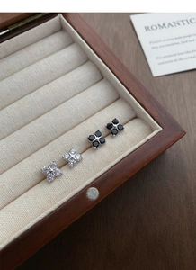 Macro detail of silver clover earrings with sparkling cubic zirconia in a jewelry box