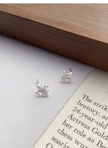Close-up of brushed S925 silver fleur-de-lis stud earrings with delicate center crystal