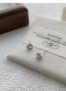 Macro view of dainty S999 silver heart stud earrings with sparkling pave-set cubic zirconia