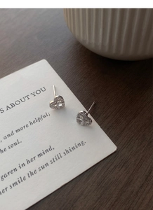 Macro view of S925 silver heart stud earrings with ribbon bow and sparkling zircon stones
