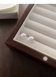 Macro shot of silver stud earrings featuring brushed texture and starburst celestial patterns