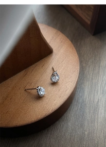 Macro shot of S999 sterling silver snake earrings with zircons on wooden stand