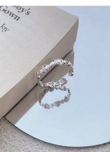 Macro detail of silver S925 heart ring with hollow heart pattern and adjustable band