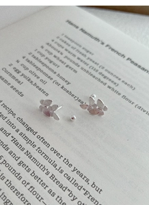 Detail of silver butterfly studs with brushed texture on open recipe book background