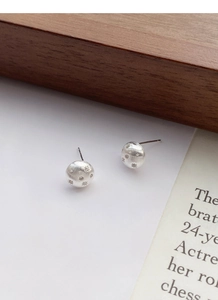 Macro shot of S925 sterling silver brushed hemisphere earrings with starburst patterns