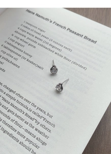 Macro shot of silver snake-shaped stud earrings with sparkling cubic zirconia on book pages