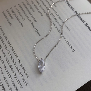 Minimalist S925 silver necklace with marquise cut zircon pendant on a vintage book