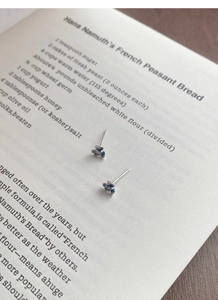 Détail macro de boucles d'oreilles iris en argent S999 avec pétales en émail et diamant