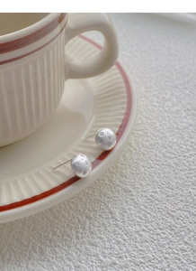 Macro detail of S925 sterling silver brushed round star stud earring on a ceramic saucer