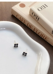 Close-up of S999 silver four-leaf clover stud earrings with black stones on white tray