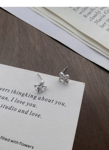 Macro detail of matte S925 sterling silver fleur-de-lis earrings with centered diamonds
