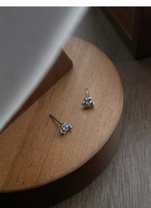 Détail macro de boucles d'oreilles iris en argent S999 avec émail bleu et zircon central
