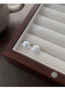 Macro shot of silver round ball earrings with brushed matte texture and star motifs