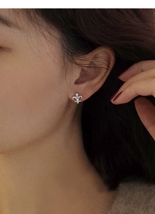 Close-up of S925 sterling silver iris flower stud earring worn by a female model