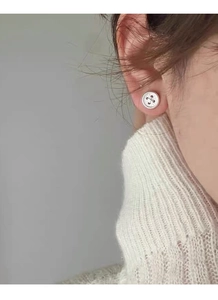 Detailed close-up of S999 sterling silver button earrings on model ear with silver finish