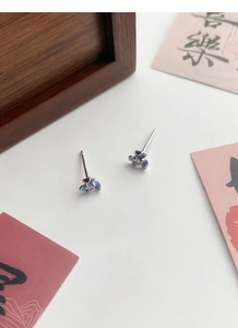 Gros plan de boucles d'oreilles iris en argent S999 avec émail bleu et zircon central