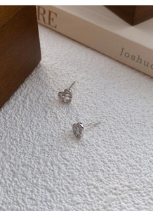 Macro view of S999 silver bow heart stud earrings with sparkling cubic zirconia stones
