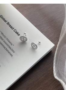 Detailed macro view of S999 sterling silver button earrings on a vintage magazine base