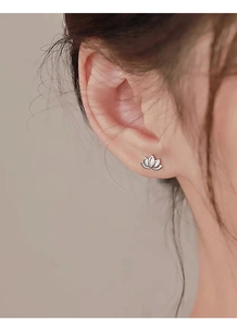 Close-up of S999 sterling silver lotus stud earrings with crystals on an earlobe