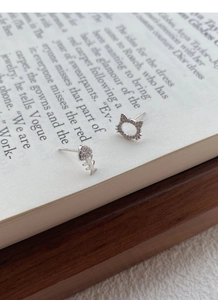 Detail view of asymmetric S999 silver cat and fishbone stud earrings with zircon inlay