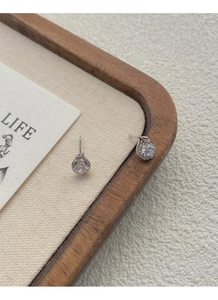 Macro view of S999 silver snake stud earrings with brilliant zircon on a wooden tray