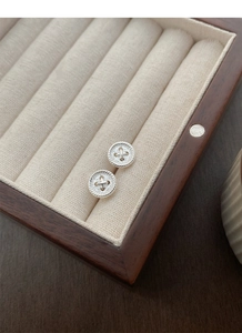 Macro detail of S999 silver button earrings with cross-stitch and rope textured edges