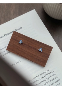 Détail de boucles d'oreilles iris en argent S999 et émail bleu avec zircon sur bois