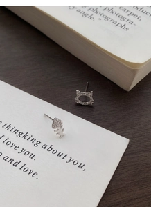 Detailed view of silver cat and fishbone stud earrings with sparkling white cubic zirconia