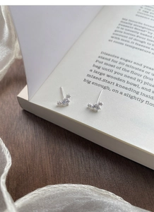 Detailed shot of sparkling S999 silver stud earrings with zircon on an open book