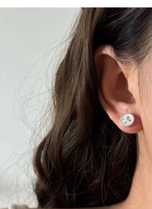 Close-up of S999 sterling silver button stud earring with textured radial patterns on ear