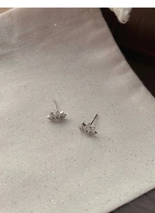 Macro shot of S999 sterling silver lotus stud earrings on a textured fabric pouch