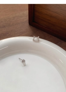 Close-up of asymmetric S999 silver cat and fish bone earrings with pavé zircons