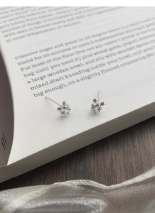 Gros plan de boucles d'oreilles en argent S999 avec zircon carré sur un livre