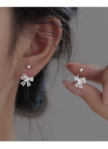 Gros plan des boucles d'oreilles nœud argentées avec motifs de cœur et fermoir à vis
