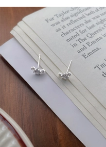 Detailed view of S999 silver sparkling zircon stud earrings on a vintage book page