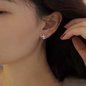 Elegant S925 sterling silver fleur-de-lis stud earrings on model with brushed texture