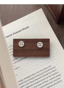 Detailed close-up of S999 sterling silver button stud earrings on vintage wooden display