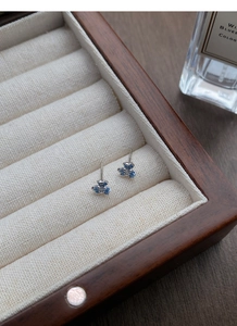 Détail de boucles d'oreilles iris bleus avec pétales émaillés et centres zircon
