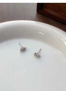 Macro detail of minimalist S999 sterling silver lotus stud earrings on ceramic tray