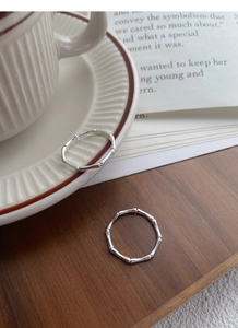 Detailed view of S999 silver bamboo style rings resting on a rustic wooden table