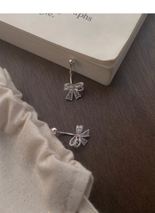 Gros plan de boucles d'oreilles nœud en argent S999 évidé sur un fond vintage