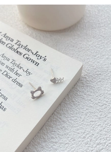 Macro shot of S999 silver cat and fishbone stud earrings with white zircons on a book